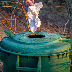 Una persona botando la basura en un basurero