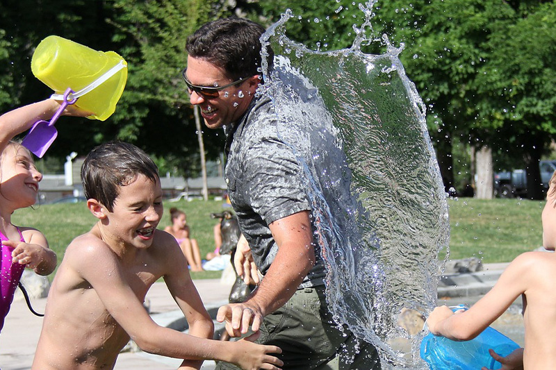 Niños y señores jugando con agua y riendo