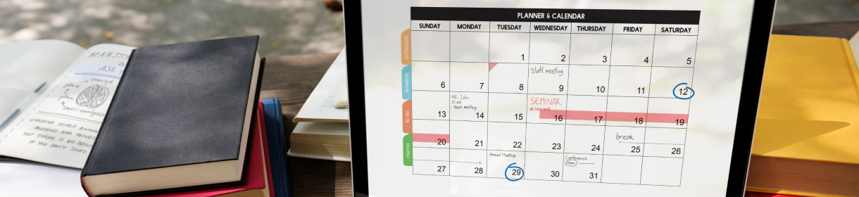 Calendario mensual digital con fechas marcadas, junto a cuadernos y libros sobre una mesa.