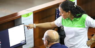 Fotografía de una trabajadora de la Biblioteca EPM ayudnado a un usuario en un computador