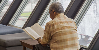 Fotografía de un señor leyendo un libro al interior de la Biblioteca EPM
