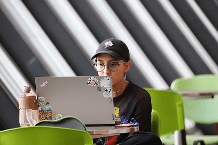 Fotografía de una mujer usando un computador portátil al interior de la Biblioteca EPM