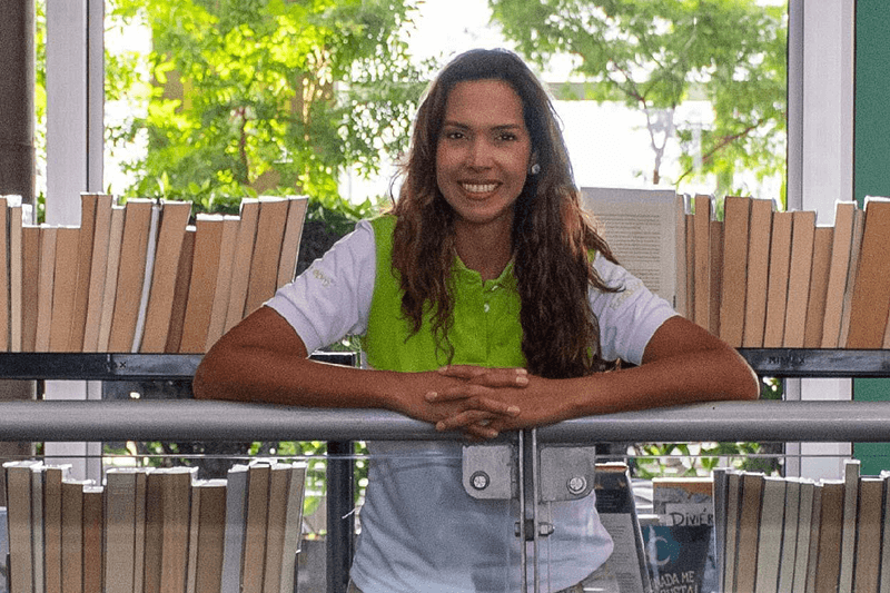 Fotografía de una mujer sonriendo al interior de la Biblioteca EPM