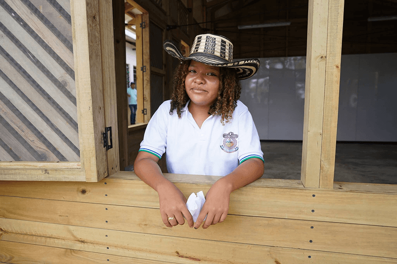 Fotografía de una niña en una ventana con un sombrero vueltiao