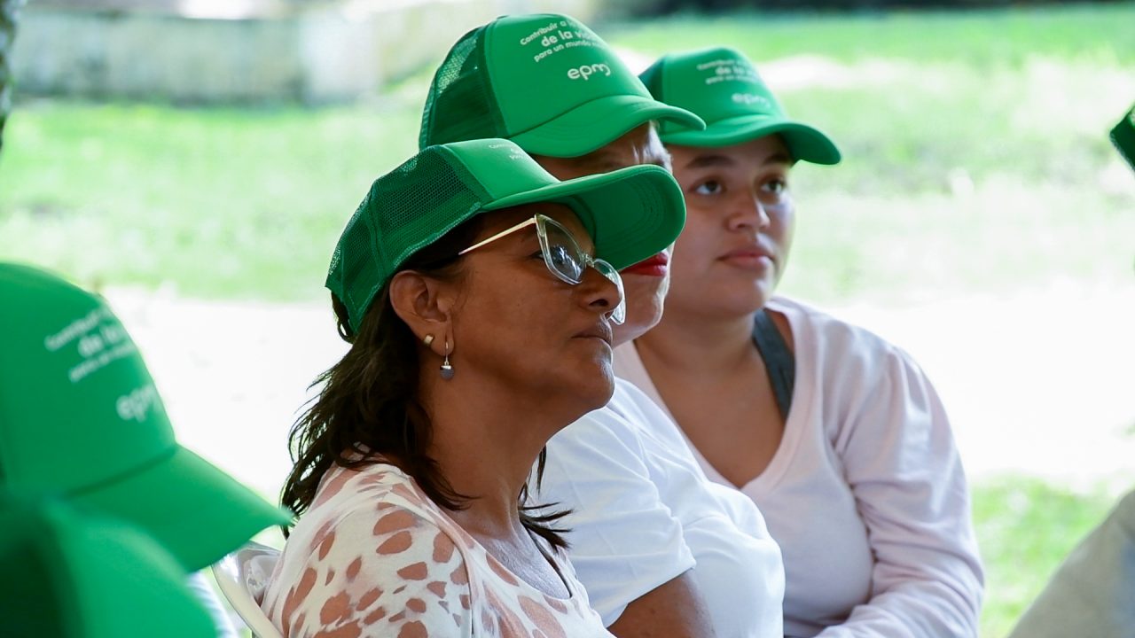 Participantes de una actividad comunitaria escuchan atentamente durante una jornada educativa al aire libre.