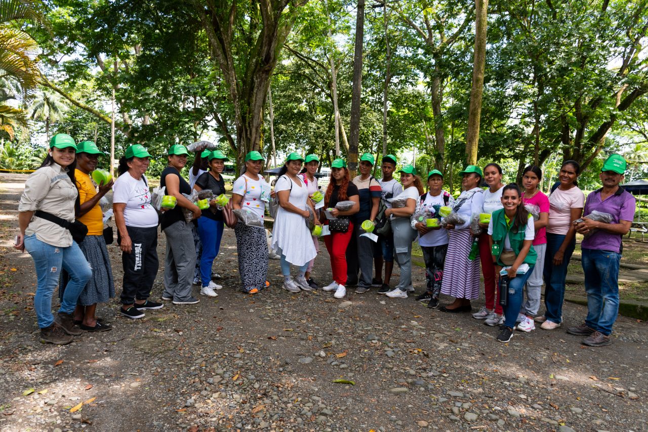 Grupo de personas con gorras verdes reunidas en un entorno natural durante una jornada comunitaria.