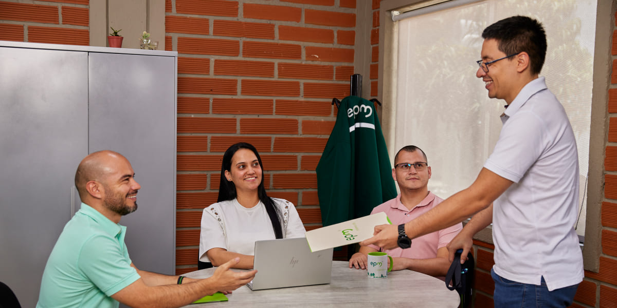 Un grupo de personas en una reunión de trabajo, con un hombre entregando un documento a otra persona, en un ambiente de oficina.