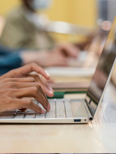 Se muestran manos de una persona escribiendo en un pc portátil 