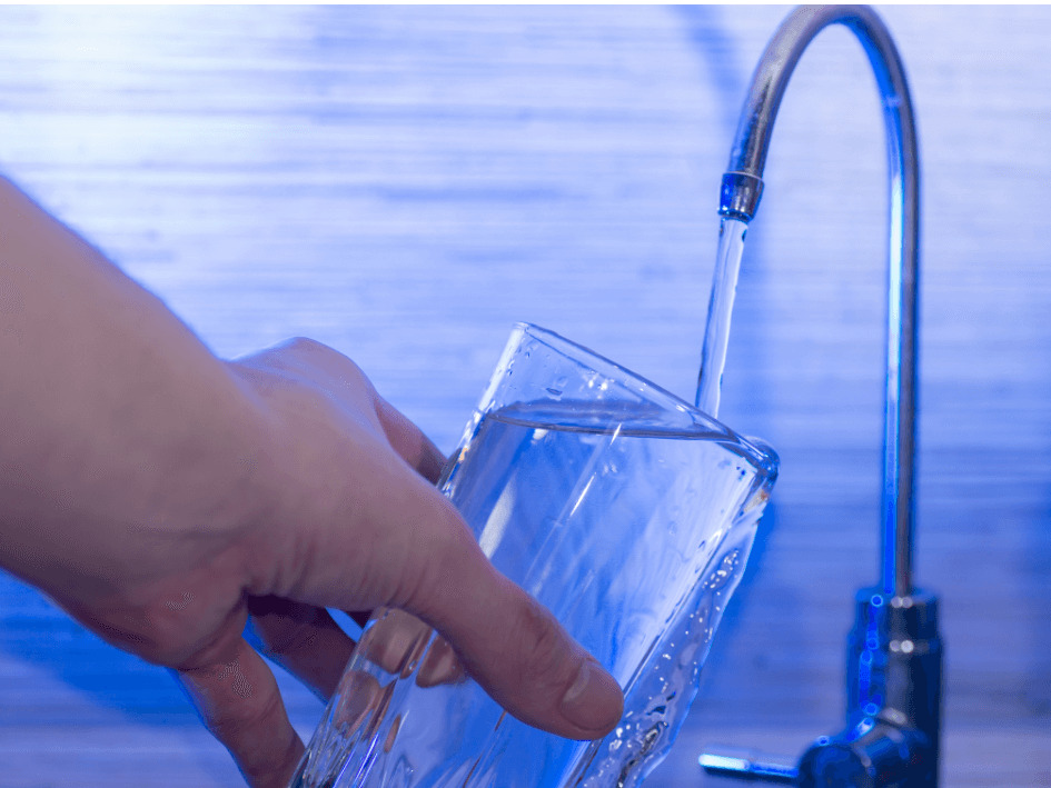 Manos con un vaso de agua llenándolo