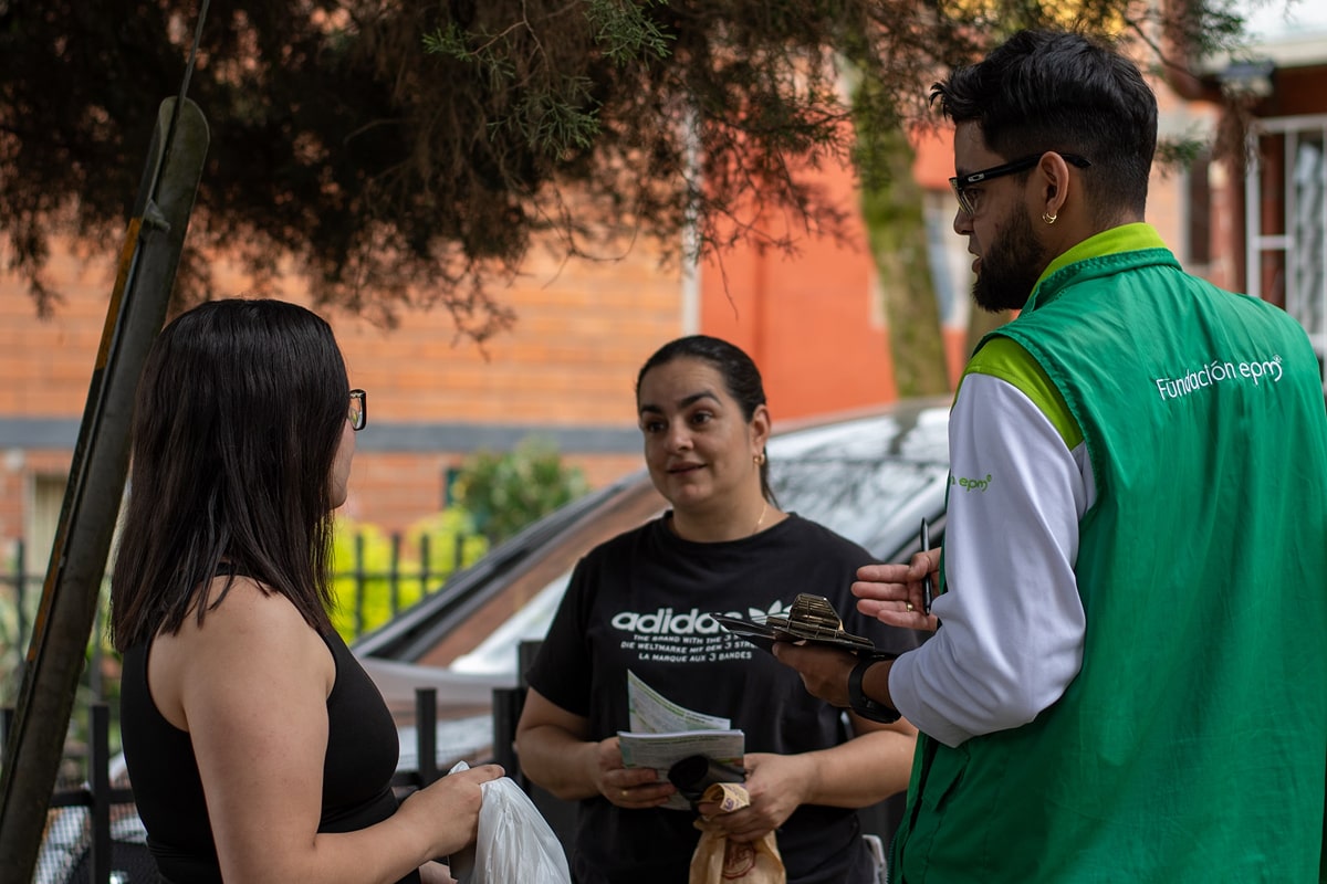Trabajadores de EPM conversando con una mujer