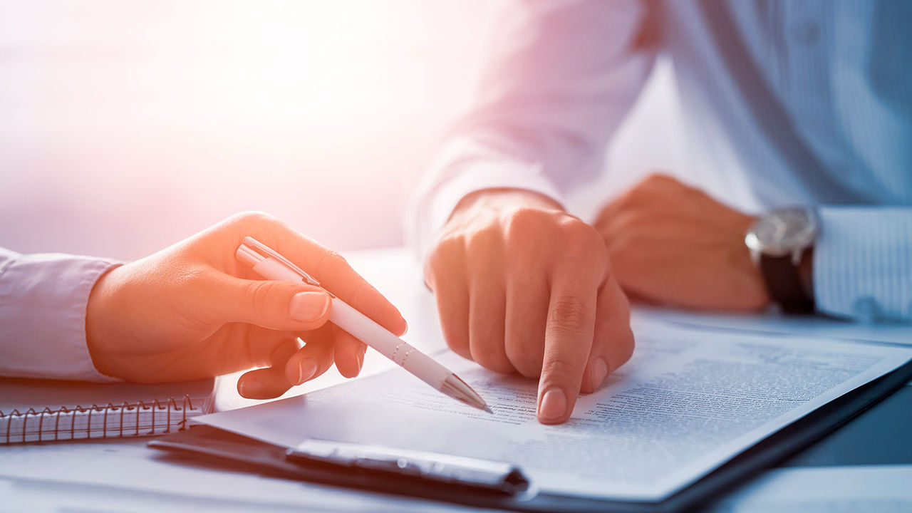 Dos personas revisando un documento sobre una mesa.